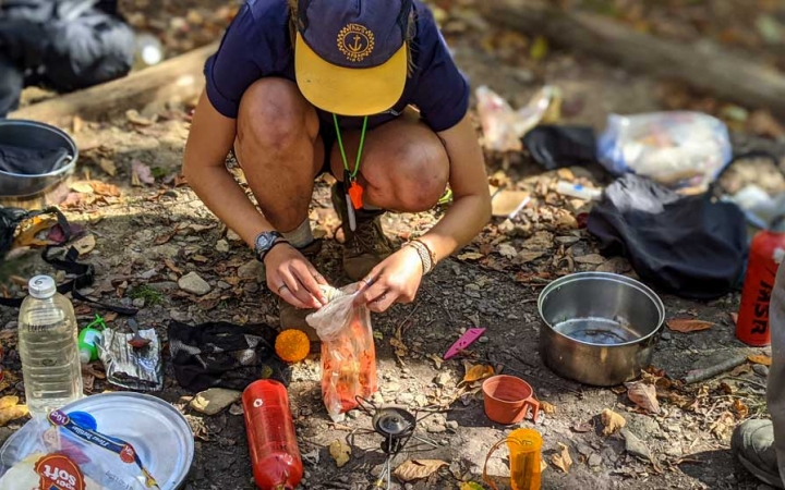 a student prepares food while on a backpacking course with outward bound